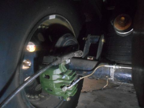 1992 Ford Bronco - A close-up view of the rear brake assembly of a vehicle, featuring a green brake caliper and a portion of the tire and wheel.