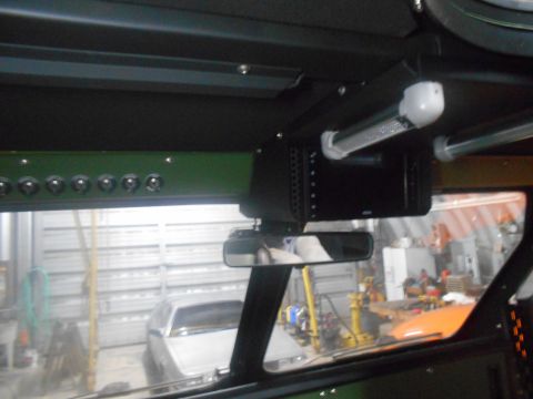 1992 Ford Bronco - Interior view of a vehicle showing a row of toggle switches on a green panel above the windshield, and a black electronic device mounted to…