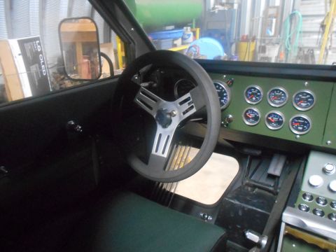 1992 Ford Bronco - The interior of a modified vehicle shows a custom dashboard with multiple gauges and a steering wheel. The driver's side door panel and a s…