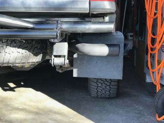 2000 Ford Explorer - The rear driver's side of a dark-colored SUV shows a mud flap mounted behind the tire, with a portion of the exhaust pipe visible. A custom…