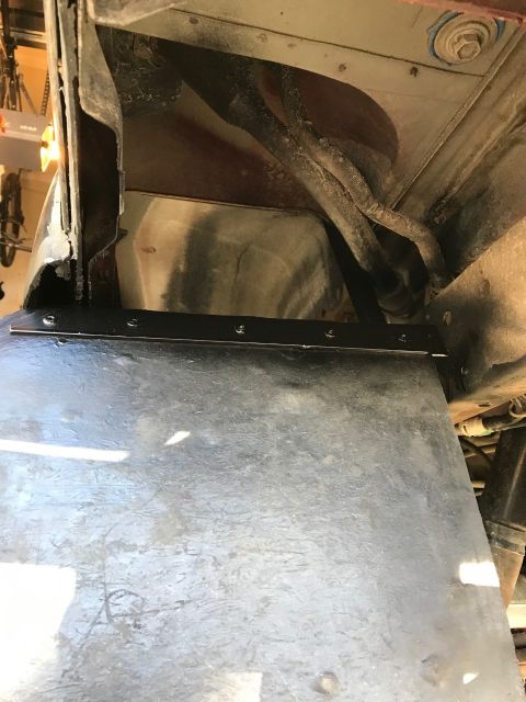 2000 Ford Explorer - The underside of a vehicle shows a black metal plate attached with screws to the frame above a larger, dark-colored panel. Visible in the b…