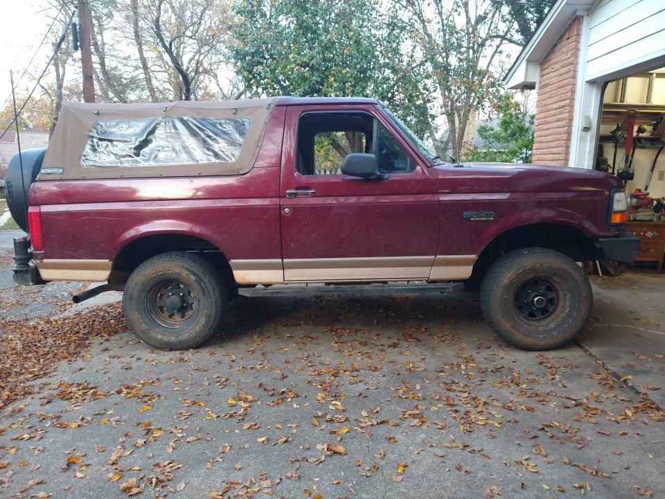 Maroon 1996 Ford Bronco side view with tan soft top