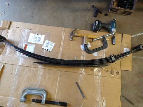 1996 Ford Bronco - Leaf spring and tools laid out on cardboard, likely for a vehicle repair or upgrade.