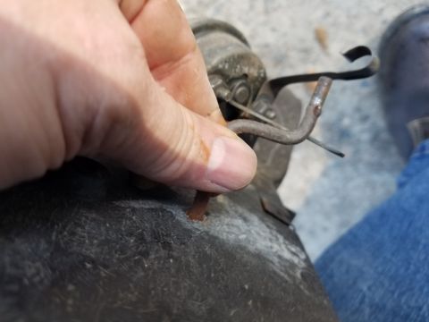 1976 Ford Ranchero - A person's hand manipulates a metal cable attached to a component, likely for a vehicle's heating system.