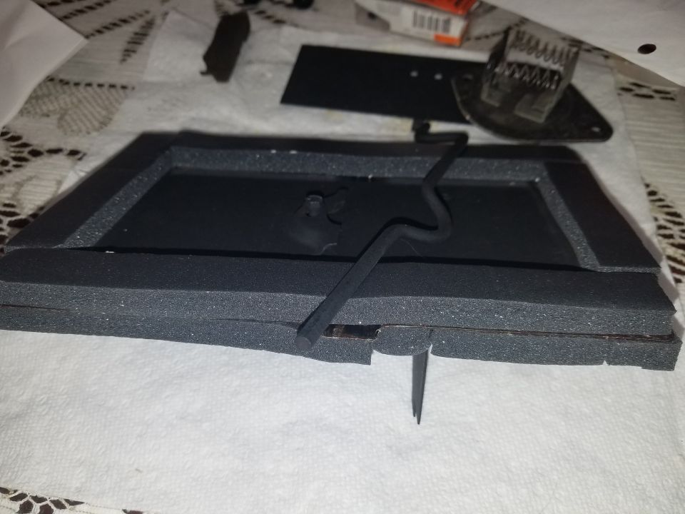 Black foam-covered rectangular part with a wavy black wire attached