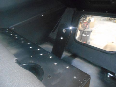 1992 Ford Bronco - Interior view of a vehicle with a grey seat and black paneling, showing a window with a vacuum cleaner outside.