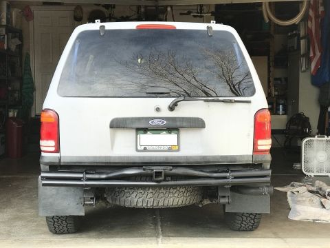 2000 Ford Explorer - The rear of a white 2000 Ford Explorer SUV is visible, parked inside a garage with a spare tire mounted below the bumper.