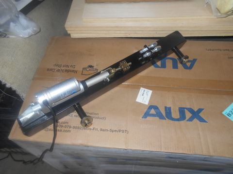 1992 Ford Bronco - Actuator assembly with silver cylinder and black bracket sits on an AUX branded box.