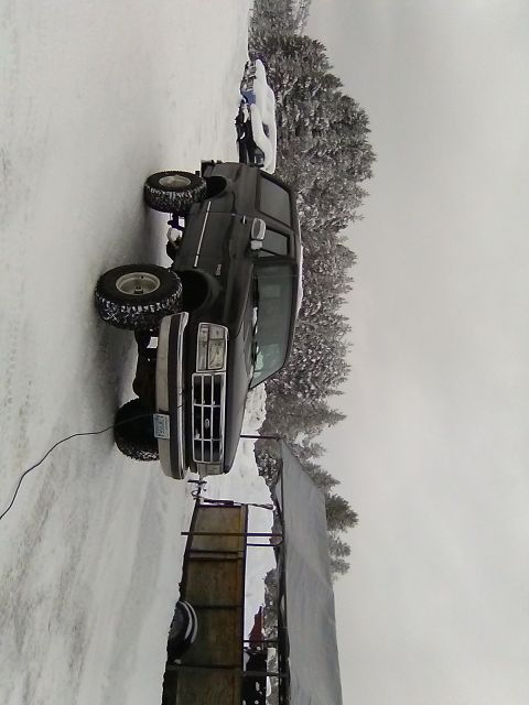 1995 Ford Bronco - A dark-colored Ford F-Series truck is parked in a snowy environment, facing forward.