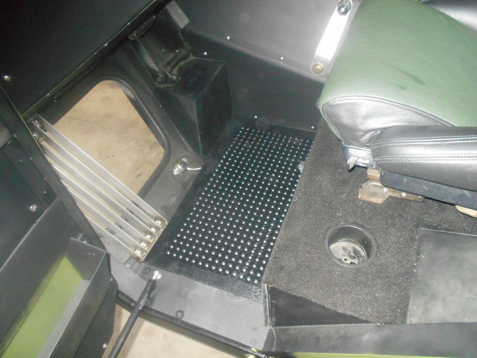 Interior view of a vehicle showing the floor, a seat, and a cup holder