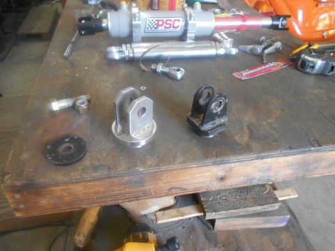 1992 Ford Bronco - Various hydraulic cylinders and mounting hardware are laid out on a wooden workbench.