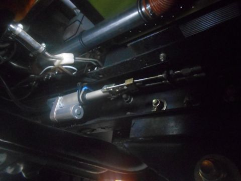 1992 Ford Bronco - Underside view of a vehicle's steering linkage, showing a silver motor and metal rods.