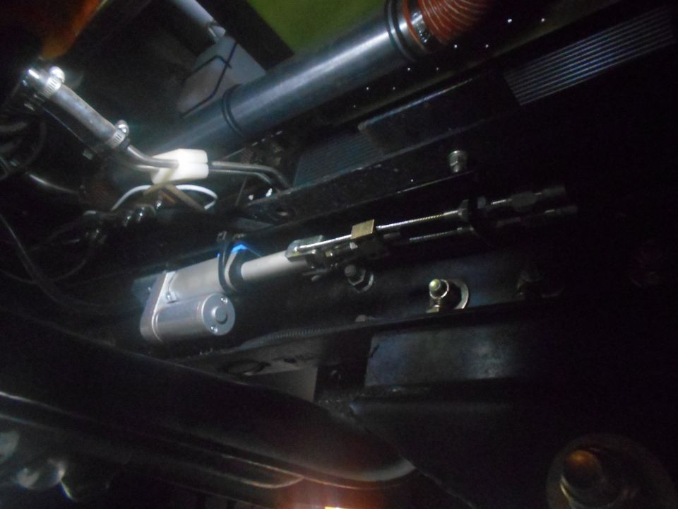 Underside view of a vehicle's steering linkage with a silver motor and metal rods