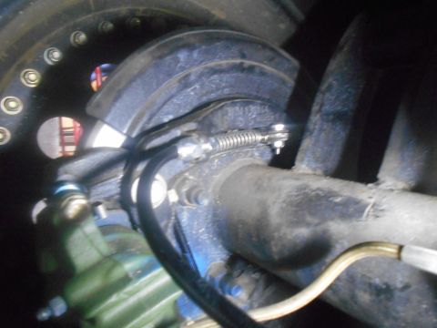 1992 Ford Bronco - Close-up view of a vehicle's rear brake assembly, showing the brake line and spring mechanism.