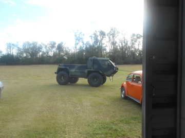 1992 Ford Bronco - A military truck and an orange car are parked in a grassy field.