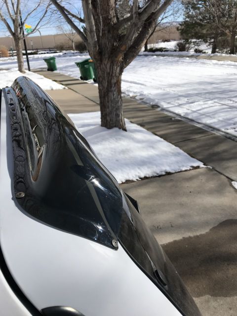 2000 Ford Explorer - A black wind deflector is mounted on the roof of a white vehicle, with snow on the ground and a tree nearby.