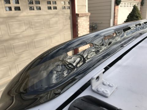 2000 Ford Explorer - Close-up of a chrome roof rack rail on a white vehicle, with a garage door reflected in the chrome.