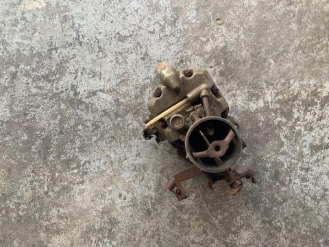1993 Ford Bronco - A close-up view of a carburetor, a crucial engine component, rests on a textured concrete surface.
