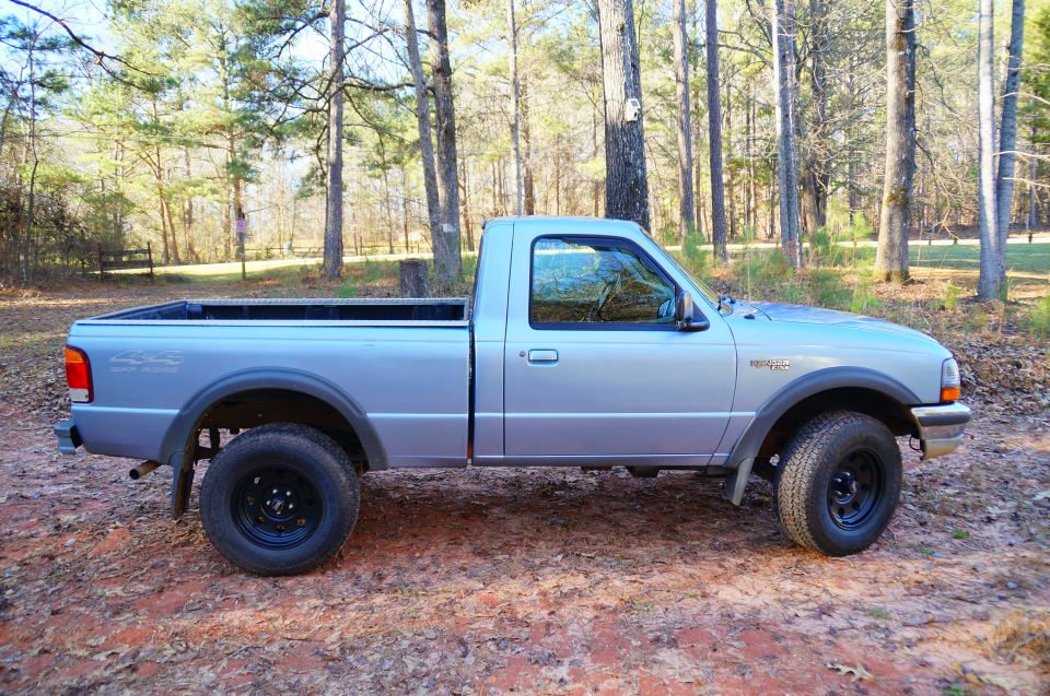 Silver 1998 Ford Ranger pickup truck, side view, parked in a forest.