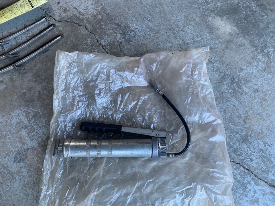 Grease gun and wiper blades on a concrete surface.