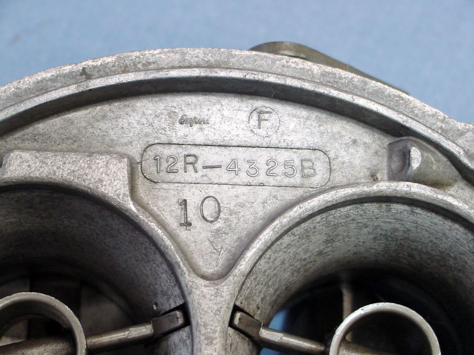 Close-up of a metal carburetor part with raised text "12R-4325B" and "10".