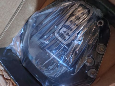 1996 Ford Bronco - A black differential cover, still in its plastic packaging, is shown inside a cardboard box. The cover has raised lettering that appears to…