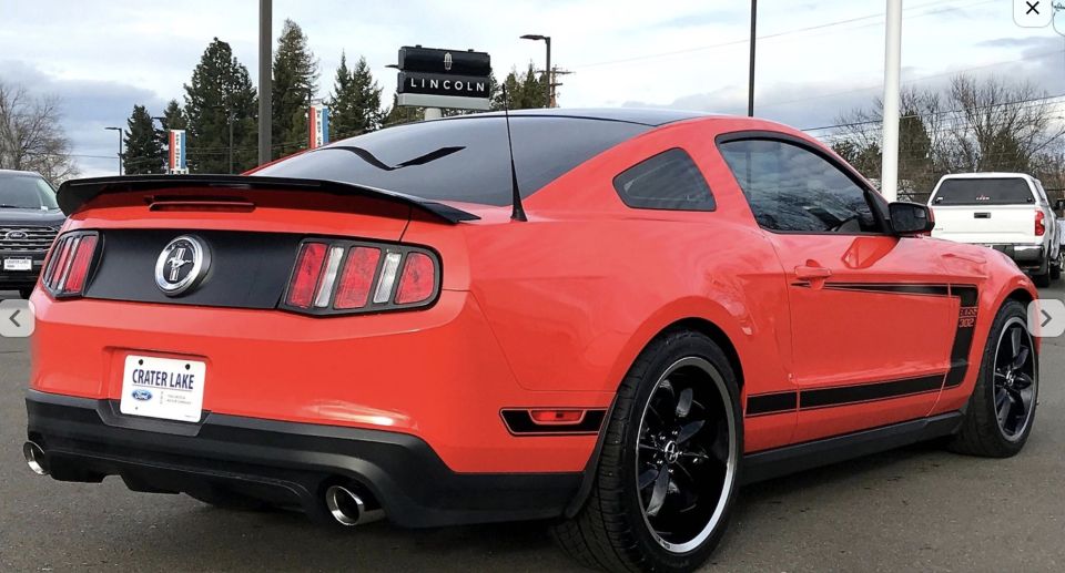 Red Ford Mustang Boss 302 with black stripes, rear view.