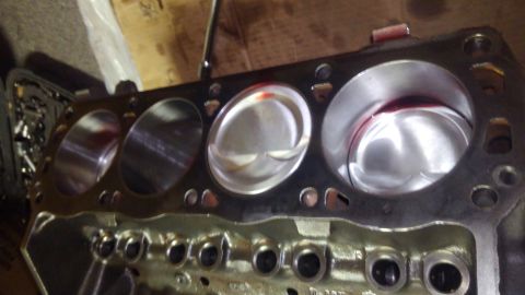 1996 Ford Bronco - A close-up view of a V8 engine block with pistons installed in the cylinders. Red fluid is visible on the top of the pistons and inside the…