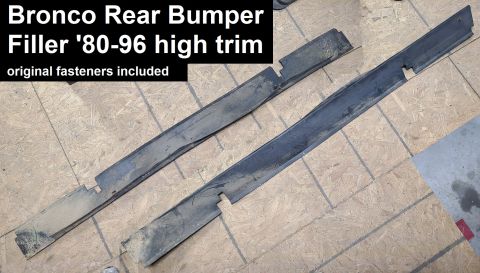 Two black plastic rear bumper filler trim pieces for 1980-1996 Ford Bronco high trim, with original fasteners