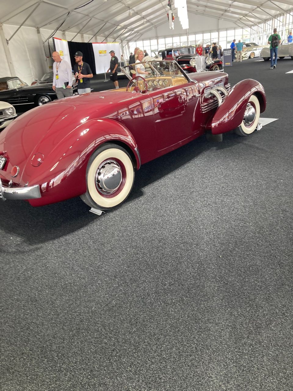 Red convertible with whitewall tires parked indoors