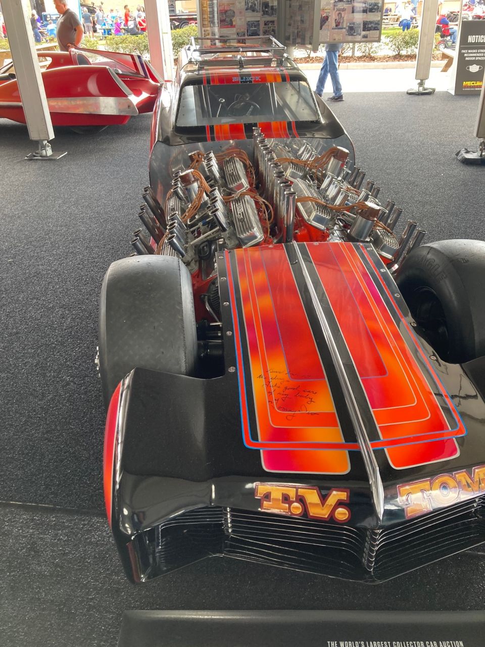 Modified drag racing car with dual engines, black and flame graphics, and "T.V. TOM" text.