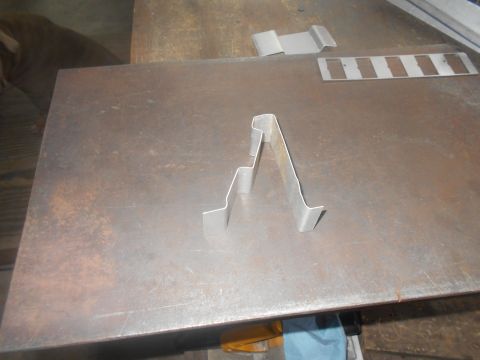 1992 Ford Bronco - A metal bracket is shown on a rusty metal surface. Other metal pieces are visible in the background.