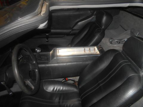 1992 Ford Bronco - The interior of a vehicle shows black leather seats, a steering wheel, and a center console with a metal storage compartment holding four b…