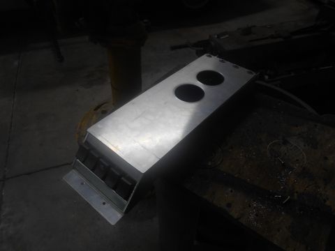 1992 Ford Bronco - A metal fabrication with two circular cutouts sits on a workbench. The fabrication has a silver, brushed metal finish and appears to be par…
