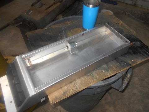 1992 Ford Bronco - A metal tray with copper piping and a silver cylinder is resting on a wooden board placed over a dark trash can. A blue insulated tumbler i…