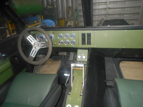 1992 Ford Bronco - The interior of a custom vehicle features a green dashboard with multiple gauges and switches, a three-spoke steering wheel, and green and…
