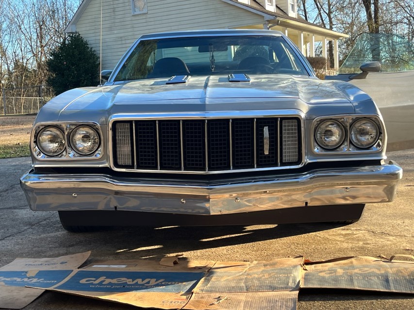 Front view of a silver classic car with a chrome bumper and grille.