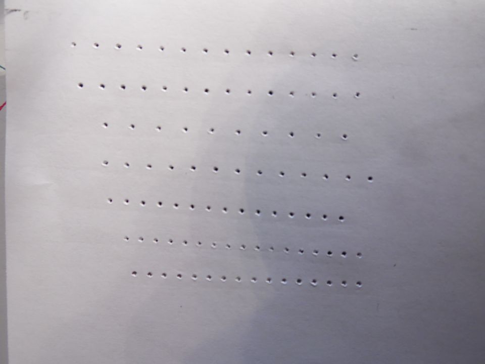 White paper with rows of small punched holes forming a dot pattern