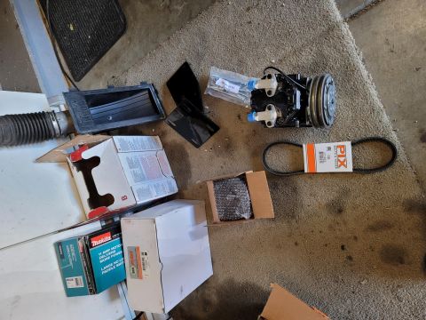 1996 Ford Bronco - A collection of automotive parts including a black air conditioning compressor, a black serpentine belt, a black air intake hose, and sever…