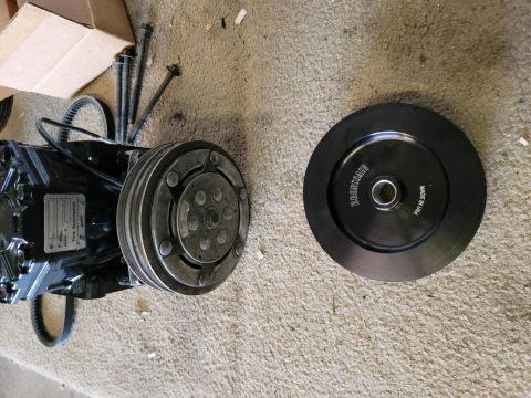 1996 Ford Bronco - A black York Automotive air conditioning compressor is shown next to a black pulley with "BRONCOAIR" and "MADE IN USA" text. Bolts and a be…