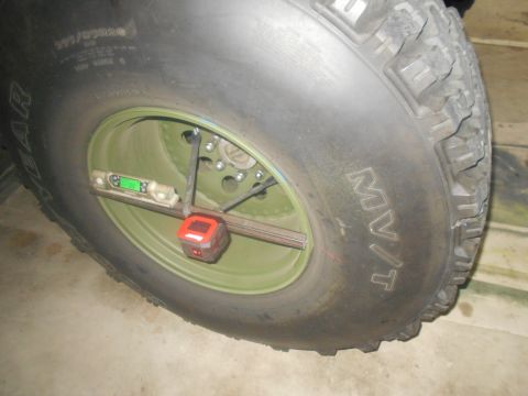 1992 Ford Bronco - A close-up view of a large tire on a vehicle, with a digital level and a laser alignment tool attached to the wheel. The tire has "M/T" mol…