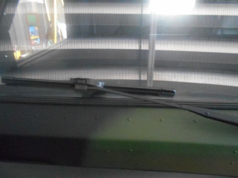 1992 Ford Bronco - View through a windshield of an escalator and a bright light source reflecting off the glass. A windshield wiper is visible in the foregrou…
