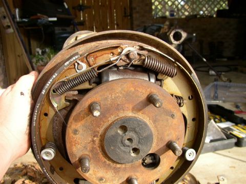 1995 Ford Bronco - Close-up view of a rusty brake drum assembly, showing internal components like springs and brake shoes.