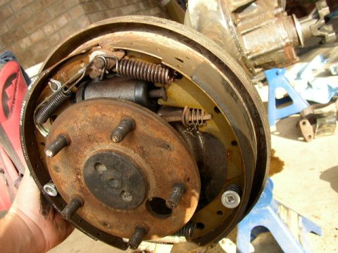 1995 Ford Bronco - Close-up of a rusty rear drum brake assembly, showing brake shoes and wheel cylinder.
