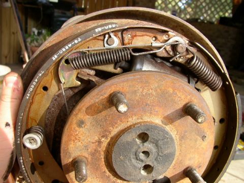 1995 Ford Bronco - This is a close-up view of a rusty drum brake assembly, showing the brake shoes and springs.