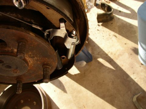 1995 Ford Bronco - Close-up view of a rusty drum brake assembly, showing the rotor, brake shoes, and adjustment mechanism.