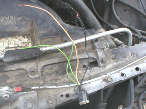 Engine bay with exposed wires and a metal bracket. Text "FAN" is visible on a black plastic shroud