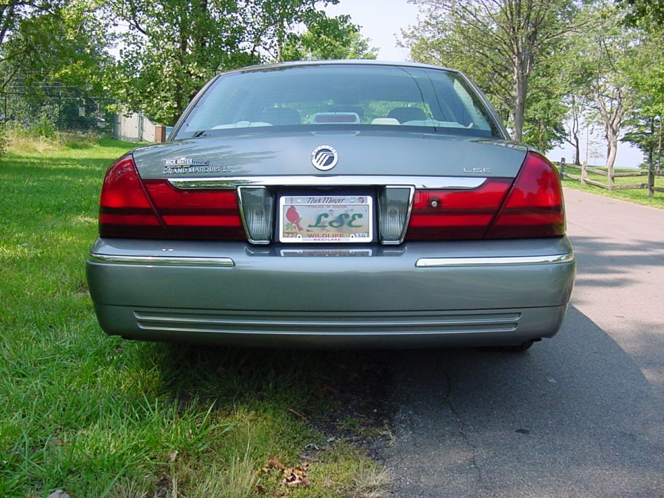 Rear view of a silver Mercury Grand Marquis LSE sedan parked on a tree-lined road