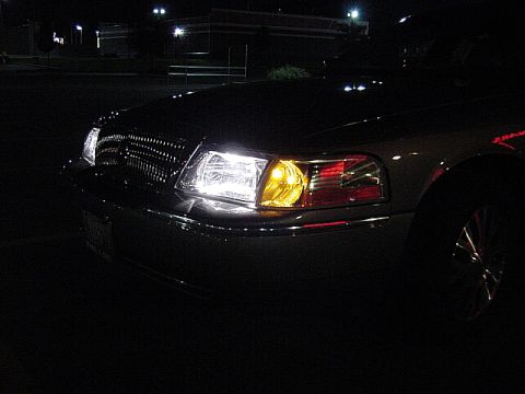 2003 Mercury Grand Marquis - Front view of a car's headlights and grille in the dark.