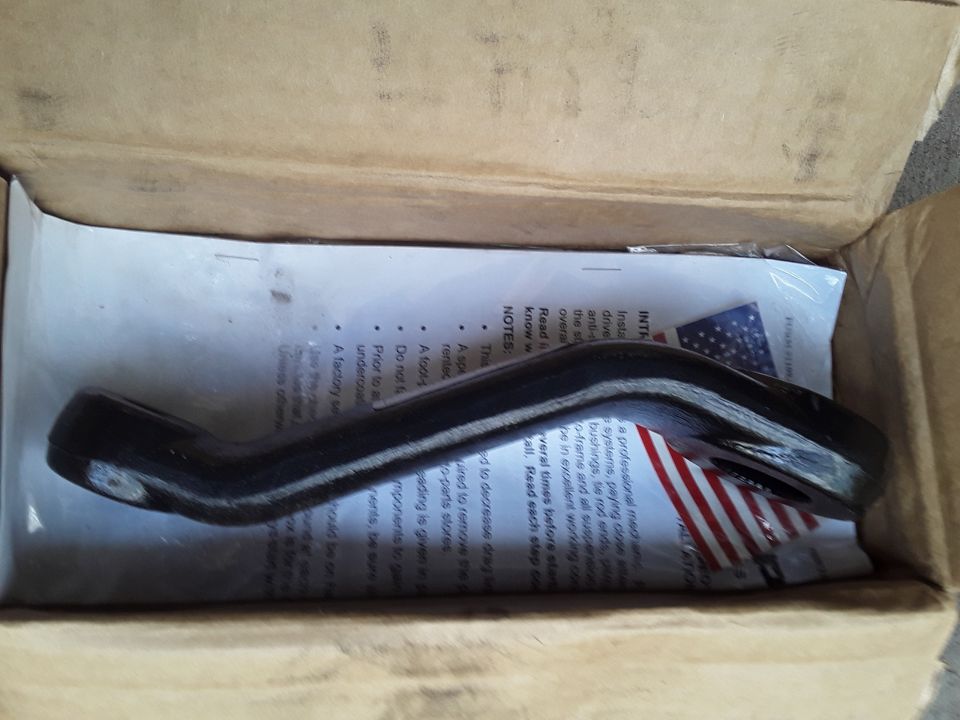 Black metal automotive part in an open box with instructions.
